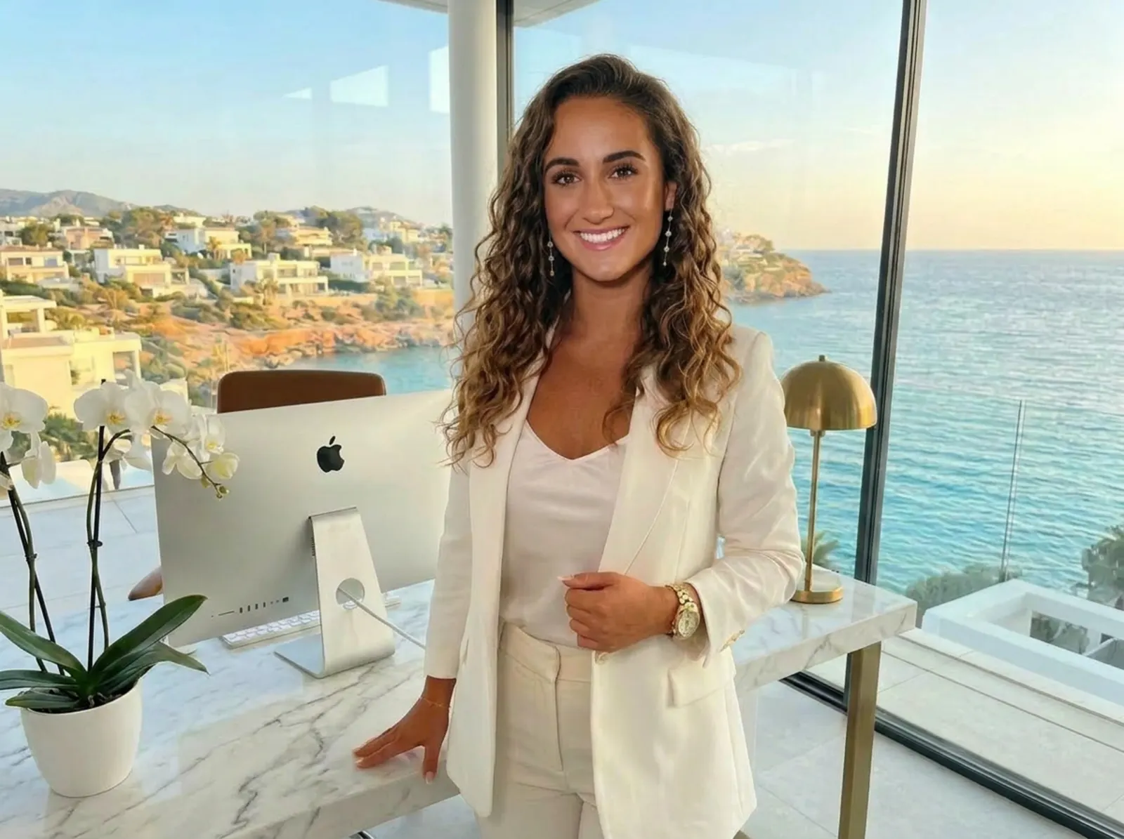 Vanessa V., founder, in a white blazer standing in her Ibiza home office